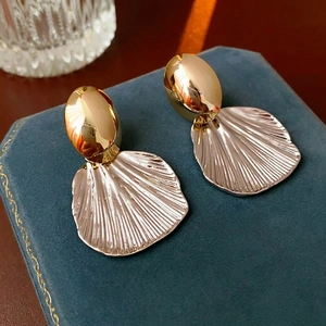 Two-tone gold and silver metallic shell earrings displayed on navy velvet jewelry box