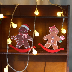Pair of Christmas wooden gingerbread man tumblers on shelf with warm fairy lights