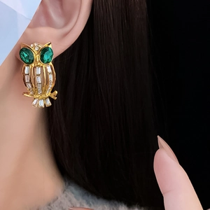 Close-up of vintage owl stud earring with green gemstone eyes and clear crystals