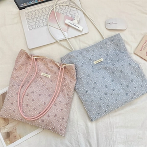 Detail of floral lace tote bag with pearl embellishments and woven handles in two colors