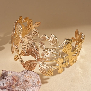 Macro detail of golden open cuff bracelet with intricate hollow flower and leaf patterns