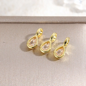 Macro detail of three 18k gold plated teardrop charms with inlaid cubic zirconia stones