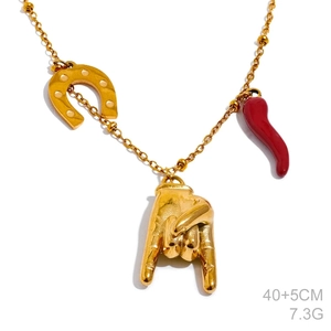 Detailed view of gold necklace featuring horseshoe, rock gesture, and red horn charms