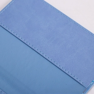 Detailed close-up showing light blue lychee-textured leather and neat stitching on passport cover