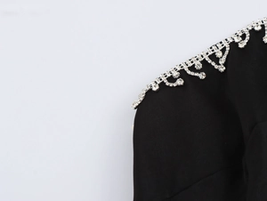 Dettaglio dell'abito in raso nero con frange di strass scintillanti e lussuose