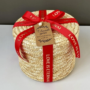 Detail of round straw gift box featuring red silk ribbon and vintage Thank You tag