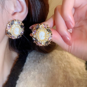 Vintage relief portrait earrings with crystals and gold finish on a female model