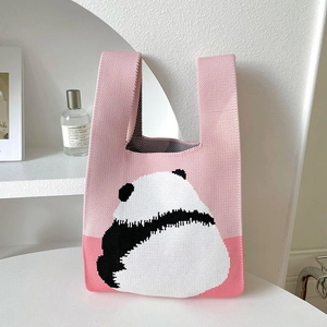 Close-up of pink knitted tote bag with cute panda pattern on a minimalist desk