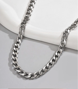 Close-up detail of silver stainless steel Cuban link chain necklace on display stand