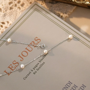 Elegant freshwater pearl necklace with silver chain on a vintage book backdrop