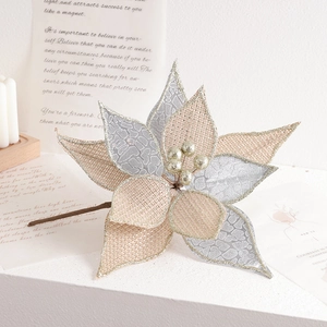 Artificial champagne gold poinsettia with glitter edges and fabric texture on white table
