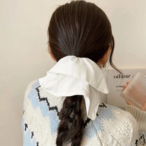 Classic white satin oversized bow scrunchie showing elegant drape on dark braided hair