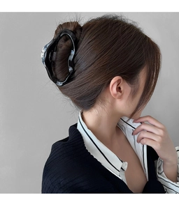 Detail view of large glossy black hair claw clip styled on woman's head from behind