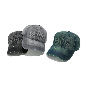 Close-up of distressed denim baseball caps with vintage holes and PARIS embroidery