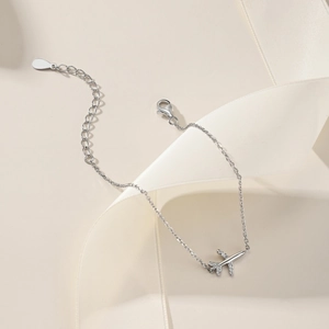 Detailed close-up of a silver airplane charm bracelet with sparkling zircon stones