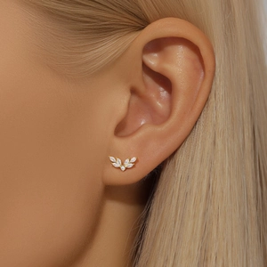 Close-up of gold leaf stud earring with marquise-cut zircons worn by a female model