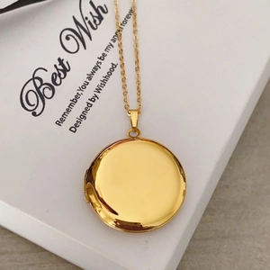 Macro shot of an openable gold round locket necklace on a Best Wish gift box