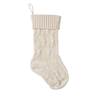 Close-up of cream knitted Christmas stocking featuring diamond patterns and cable texture