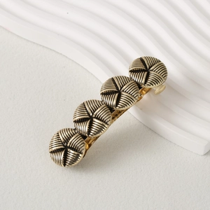 Detail of vintage bronze metal hair clip with four swirl-textured circular components