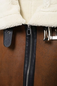 Détail du col d'un gilet en daim marron vintage avec fermeture éclair et boucle en métal