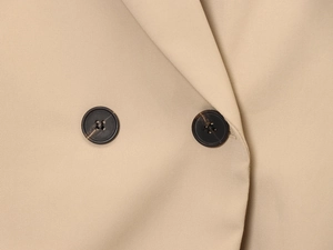 Macro shot of khaki twill fabric texture and dark brown buttons on a slim blazer