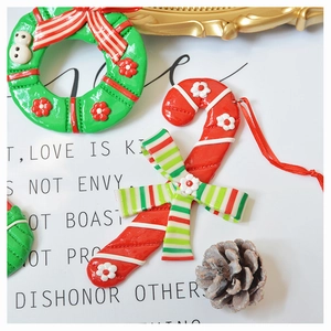 Close-up of handmade polymer clay Christmas wreath and candy cane ornaments with bows
