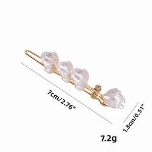 Golden hair clip with shell-textured leaves and small rhinestones on white background