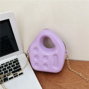 Mini purple PVC jelly handbag with golden chain strap for girls and women on a desk
