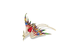 Detail of golden phoenix brooch with colorful enamel wings and a large red oval gemstone