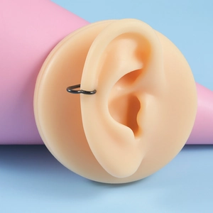 Vue macro d'un earcuff en forme de cœur noir mat en acier inoxydable sur un modèle d'oreille