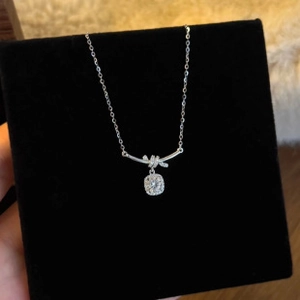 Close-up of silver knot pendant and square cubic zirconia on a fine chain necklace