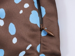 Close-up of brown satin fabric with blue dots and a concealed zipper detail