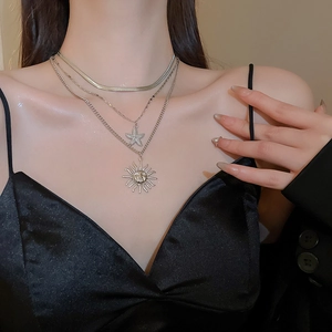 Detail of layered gold necklace with wrinkled starfish and sun pendants on a model