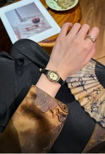 Elegant oval gold watch with diamond bezel and black leather strap on female wrist