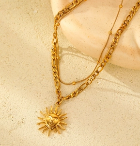Detail of double-layer 18K gold-plated cuban chain necklace with sun face pendant