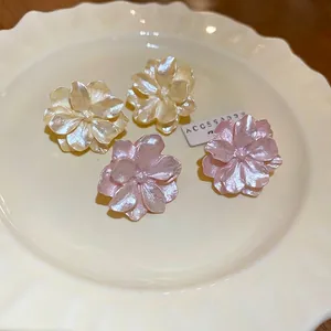 Elegant camellia flower earrings in white and pink resin with pearl finish on ceramic plate