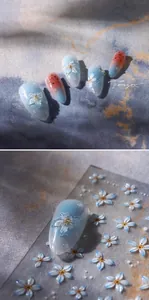 Dettaglio di adesivi per unghie blu sfumato con fiori in rilievo 3D e dettagli oro