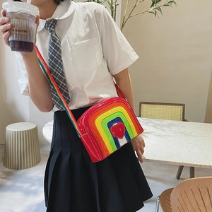 Close-up of rainbow striped crossbody bag with red heart and matching strap detail