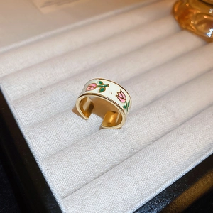 Close-up of a gold-plated open ring with white enamel and pink tulip floral patterns