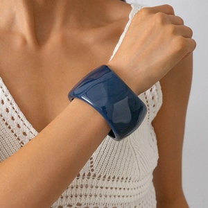 Close-up of wide navy blue resin bangle with high gloss finish on a model's arm