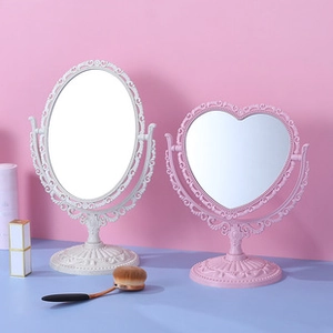 Detail of vintage carved makeup mirrors in oval white and heart-shaped pink designs