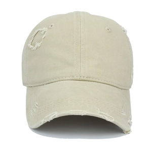 Detail of distressed beige cotton baseball cap with torn fabric and curved brim