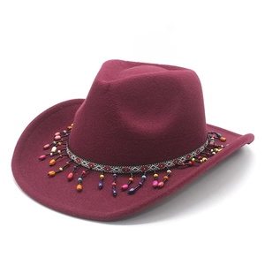 Close-up of burgundy wool cowboy hat with geometric woven band and colorful beaded tassels