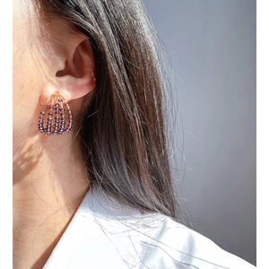 Elegant handmade purple crystal beaded gold-plated hoop earrings worn by a model
