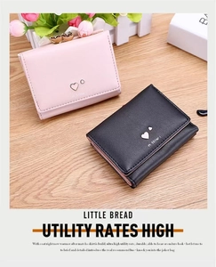 Flat lay of mini pink and black PU leather wallets with heart hardware on wood surface