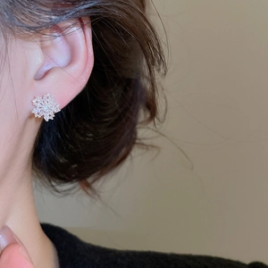 Close-up of model wearing silver flower stud earrings with sparkling cubic zirconia
