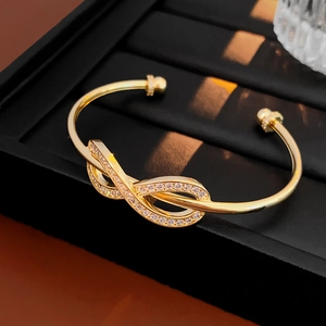 Macro shot of gold infinity knot bracelet with sparkling zircon inlay on jewelry stand