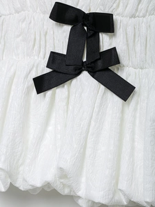 Détail macro du tissu texturé blanc avec un nœud décoratif en ruban gros-grain noir