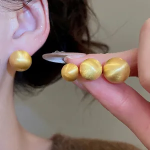 Golden brushed metal ball earrings in four sizes with model try-on comparison