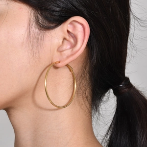 Close-up of a model wearing large minimalist golden stainless steel hoop earrings